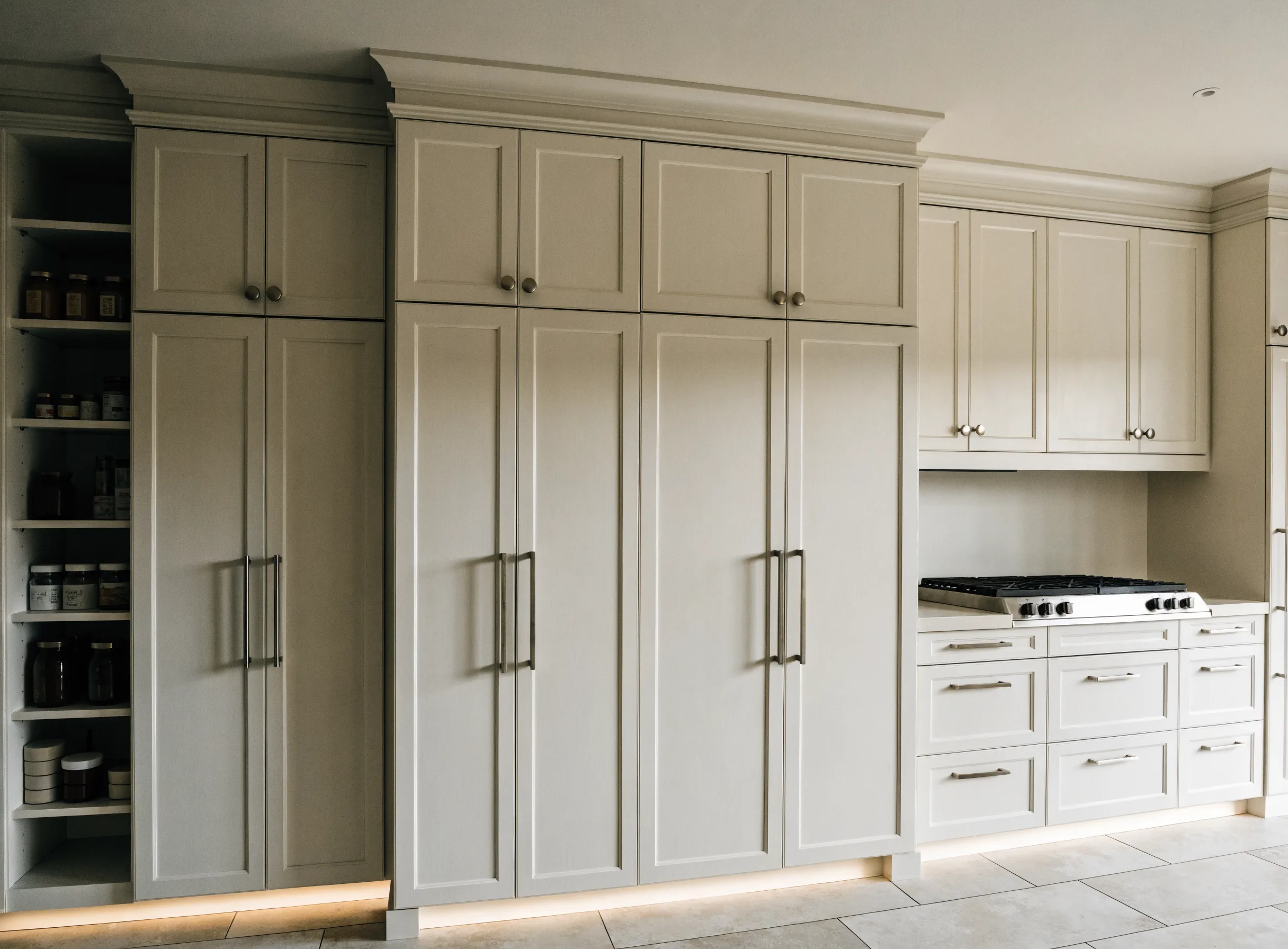 Floor-to-ceiling custom cabinetry with a tall pantry beside a panel-front refrigerator