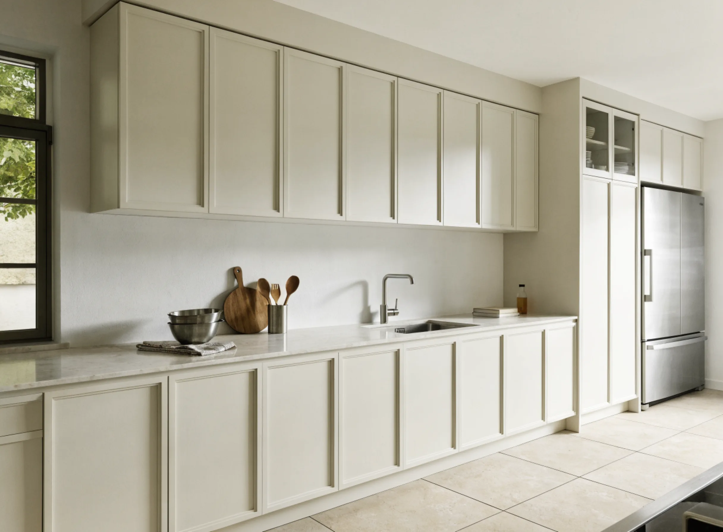 Custom cabinetry Boca Raton: a long painted cabinet run built to fit the wall end to end, with a tall pantry beside a panel front refrigerator