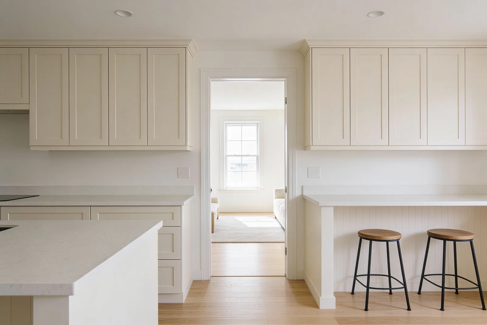 A finished compact kitchen seen from the living area, with a short peninsula and two stools