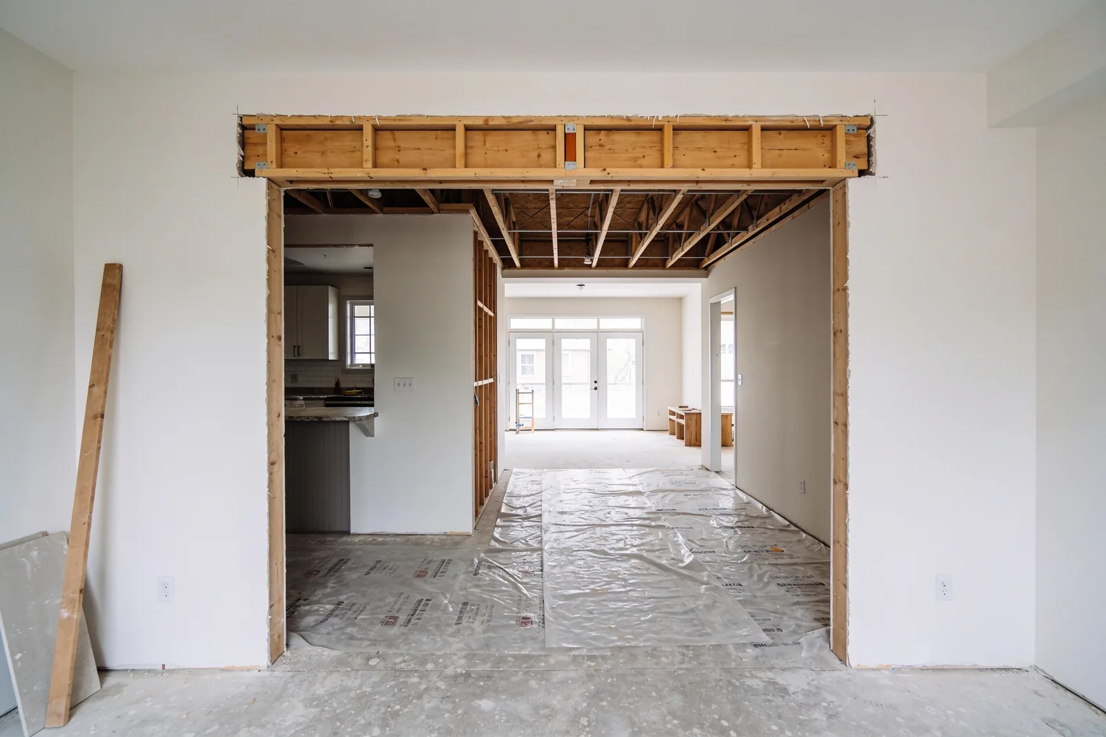 An opening cut between a kitchen and a living room, with new framing and a doubled header in place