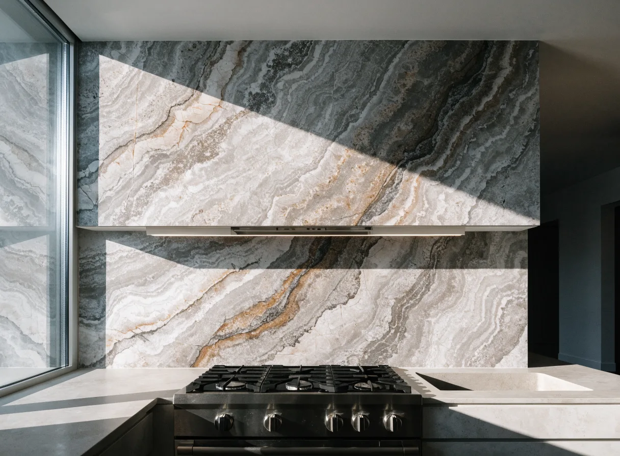 A stone slab backsplash running from the counter to the ceiling behind the range, the veining matched across the seam