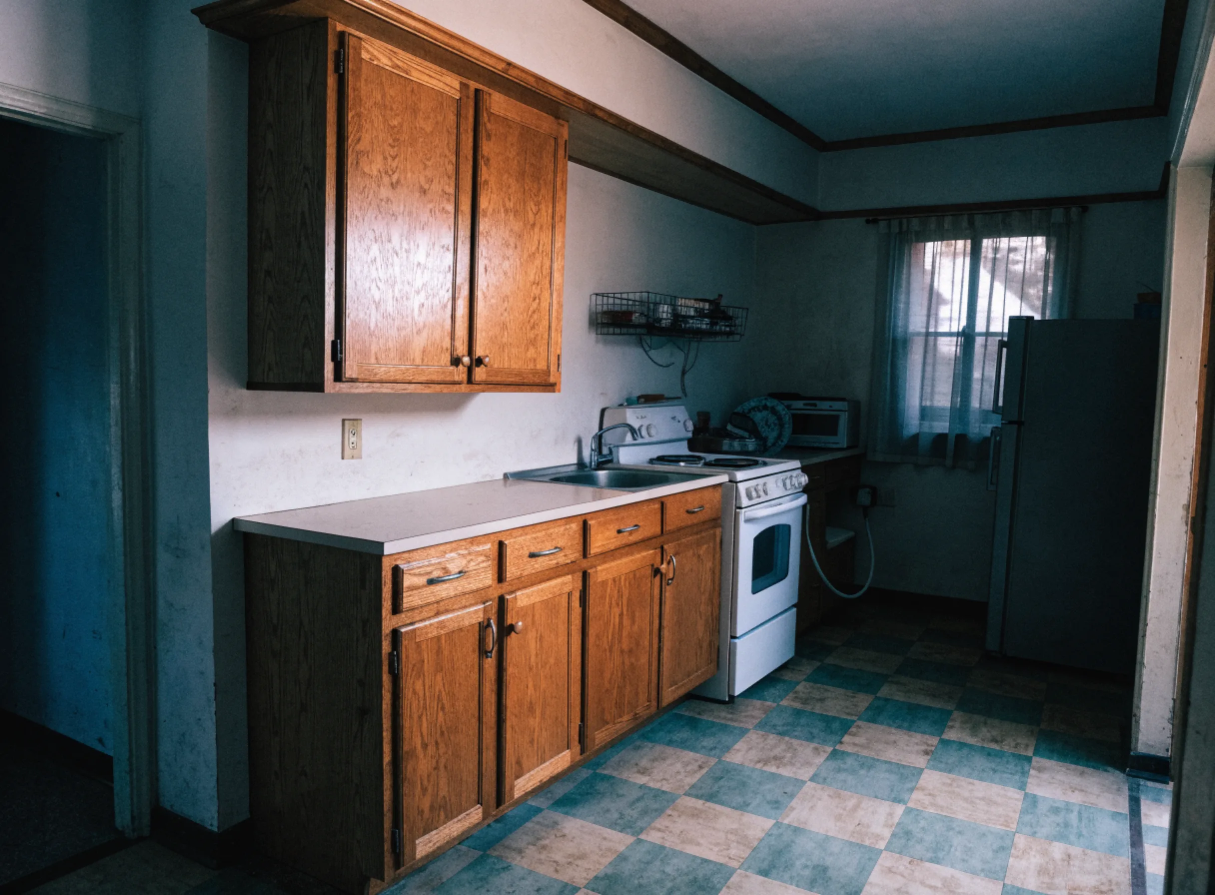 A dated galley kitchen before work, with original cabinets, a boxed soffit above them and a laminate counter