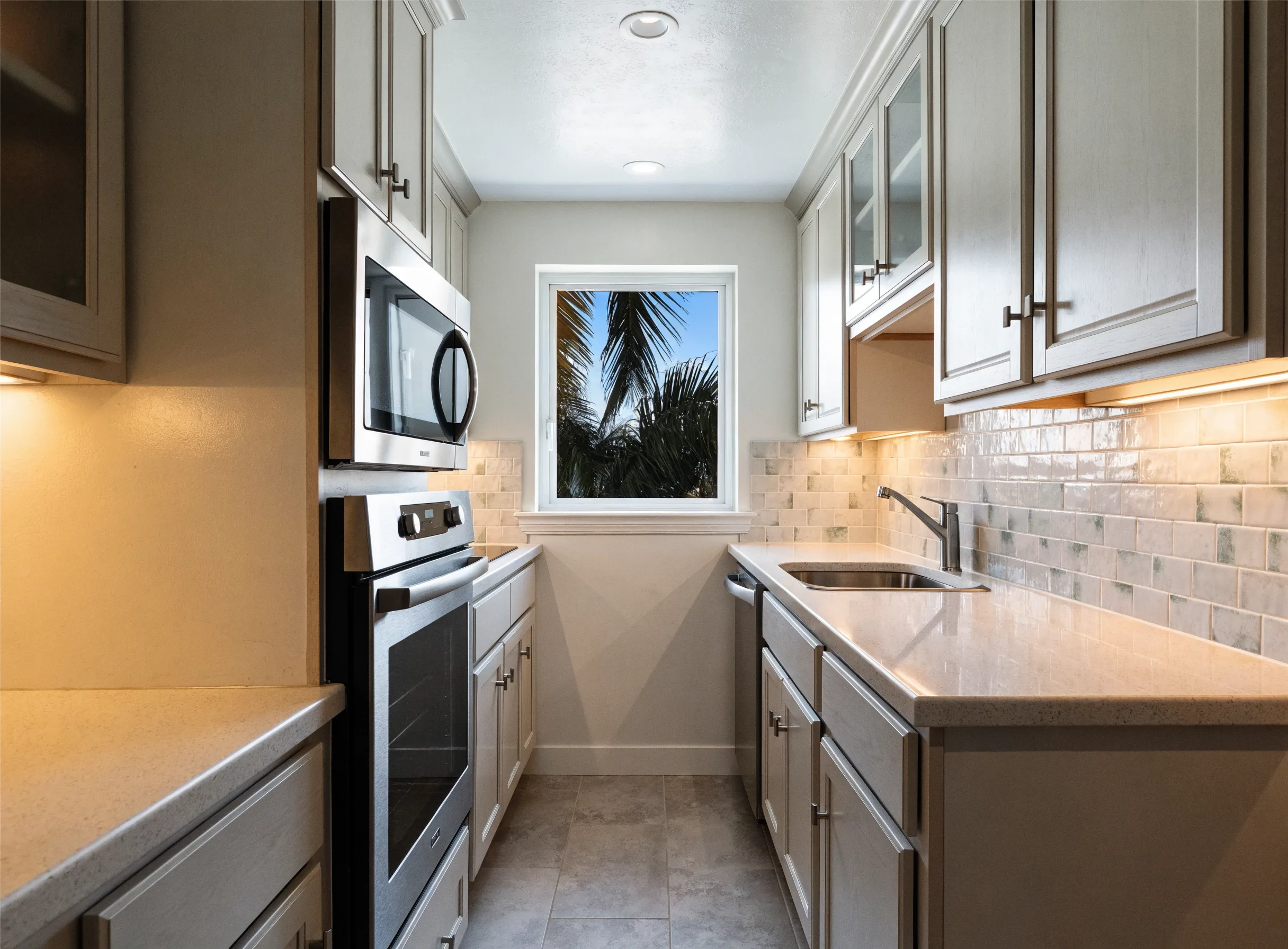 Compact galley kitchen in a coastal condo with light shaker cabinets and a window at the end of the run